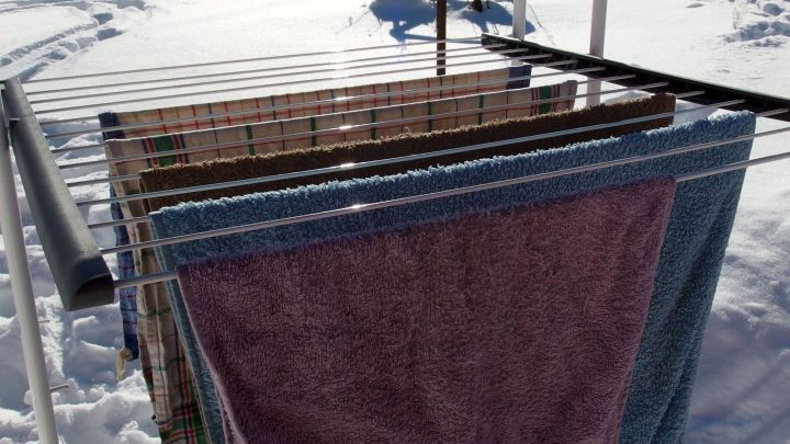 Ein W&auml;schest&auml;nder steht im Schnee, w&auml;hrend frottierte Handt&uuml;cher zum Trocknen aufgeh&auml;ngt sind.