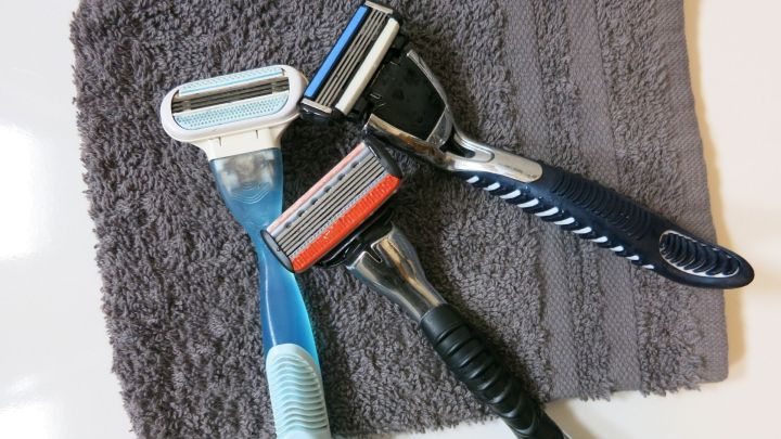 Drei Rasierklingen liegen auf einem grauen Handtuch, bereit zur Nutzung, auf einer wei&szlig;en Oberfl&auml;che.