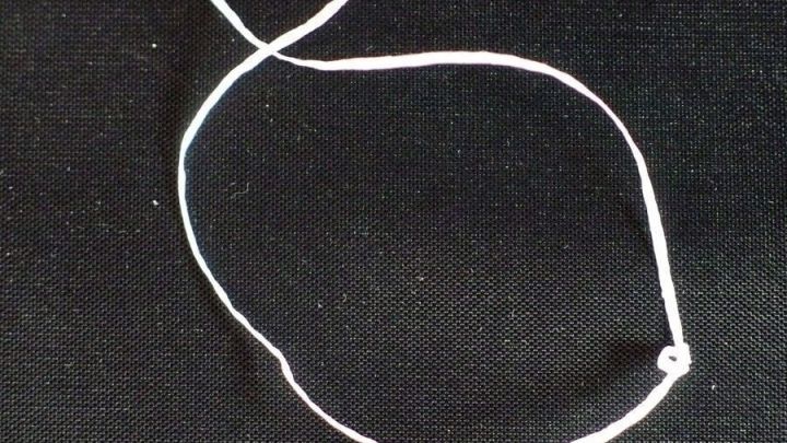 Ein Zahnseidefaden liegt auf schwarzem Untergrund, bereit, die gr&ouml;&szlig;eren Zahnzwischenr&auml;ume zu reinigen und sauber zu halten.