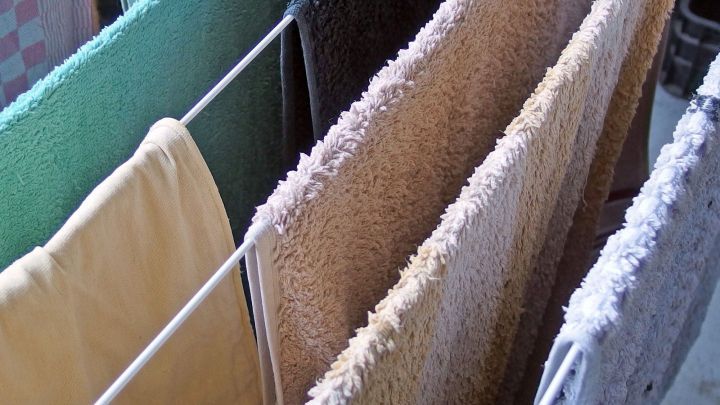 Bunte Handt&uuml;cher h&auml;ngen auf einer W&auml;scheleine und trocknen im Innenraum, weich und frisch gewaschen ohne Weichsp&uuml;ler.