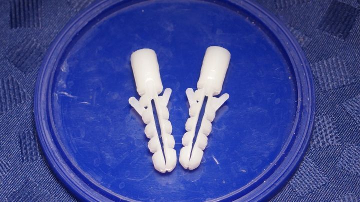 Zwei wei&szlig;e D&uuml;bel liegen auf einem blauen Untergrund, sie sind unbenutzt und zeigen keine Haltefunktion in einem Heimwerker-Kontext.