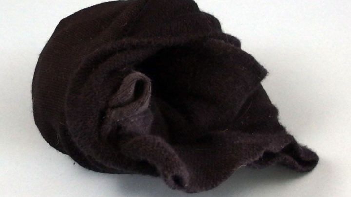 Ein brauner Sockenball liegt unordentlich auf einem neutralen Hintergrund, was das Zusammenlegen von Socken schwierig macht.