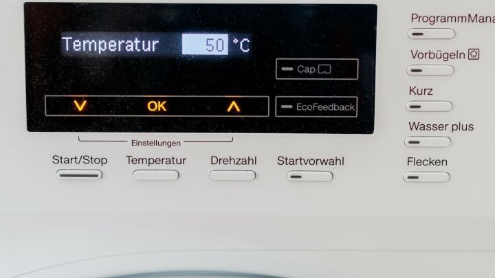 Ein Waschmaschinenanzeigendisplay zeigt die Temperatur von 50 Grad Celsius an. Die Umgebung ist technisch und modern.
