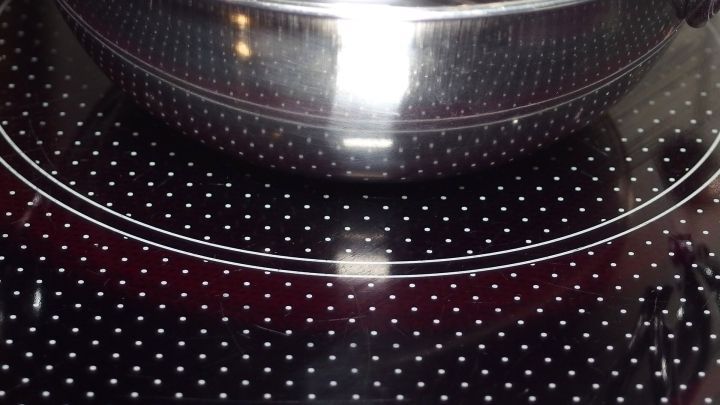 Ein gl&auml;nzendes Glaskeramikkochfeld ist sichtbar, w&auml;hrend ein Topf darauf steht, bereit zum Kochen.