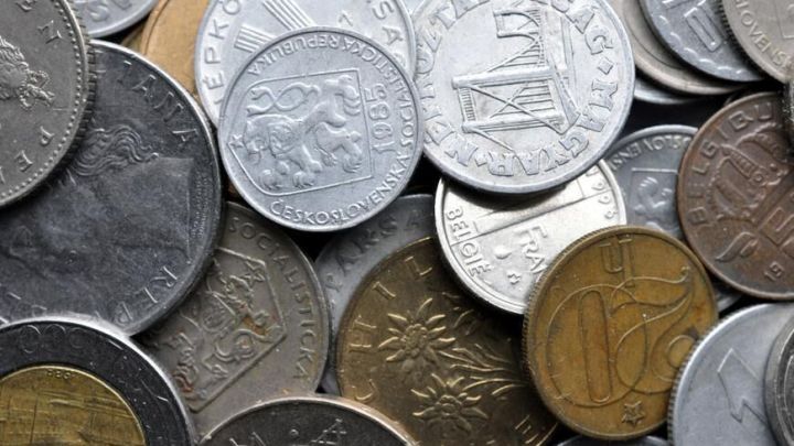 Verschiedene M&uuml;nzen, lose gestapelt, zeigen internationale Pr&auml;gungen und Designs in einem Mischmasch aus Metallen.