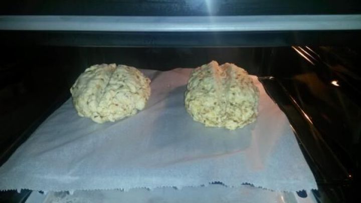 Zwei Teiglinge f&uuml;r Wei&szlig;brot und Zwiebelbrot liegen auf einem Backblech im Ofen und warten darauf, zu backen.