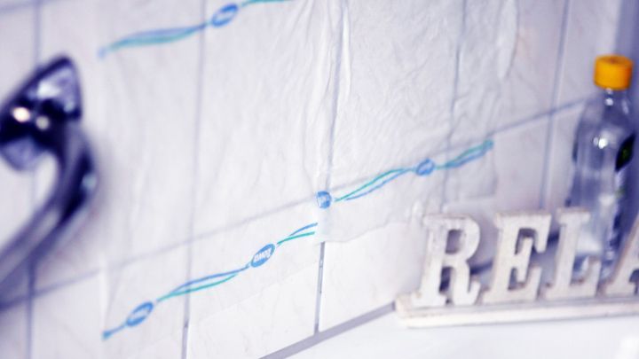 Fliesen mit Kalkablagerungen sind an einer Badewanne sichtbar, w&auml;hrend eine Flasche und das Wort &bdquo;RELAX&ldquo; im Hintergrund stehen.