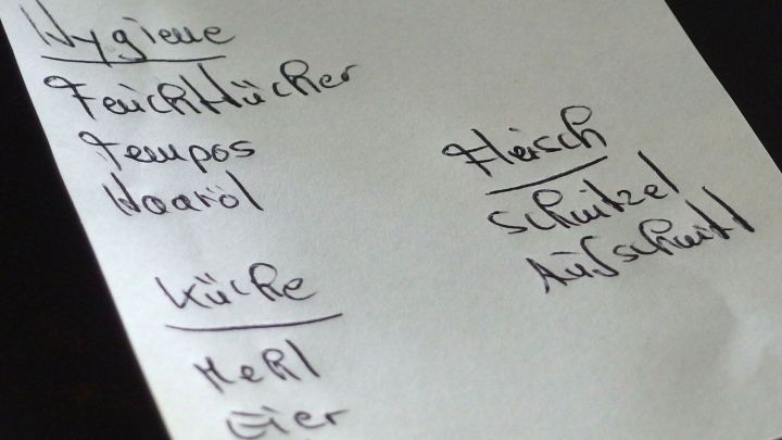 Ein Einkaufszettel liegt auf einem Tisch. Darauf sind verschiedene Lebensmittel aufgelistet, um beim Einkaufen zu helfen.