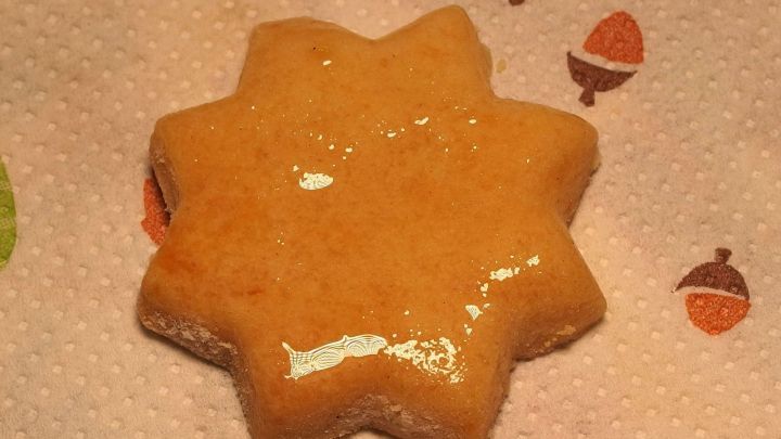 Ein gl&auml;nzendes Geb&auml;ck in Form eines Sterns liegt auf einem gemusterten Tuch, umgeben von festlicher Atmosph&auml;re.