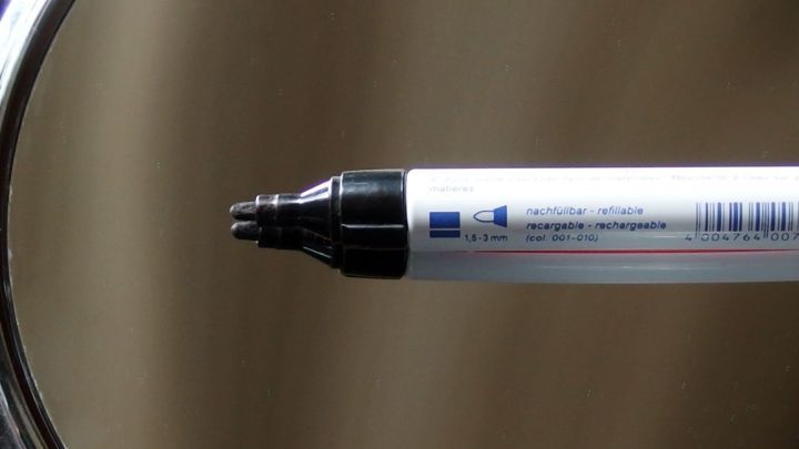 Ein Edding-Marker wird in einem Spiegel betrachtet, der gl&auml;nzende Oberfl&auml;che reflektiert den Stift.