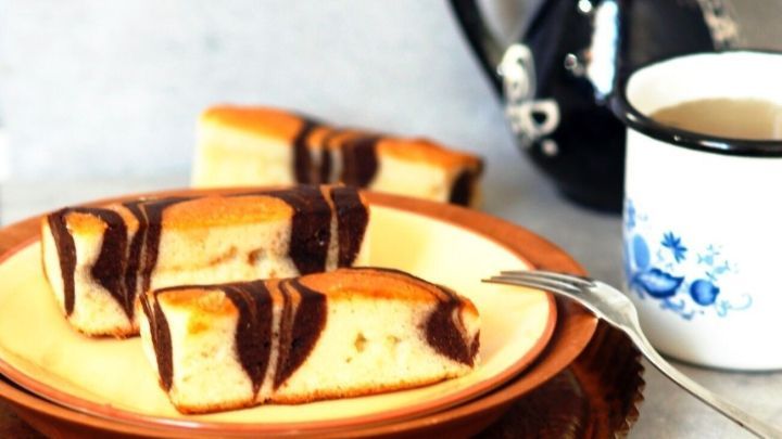 Ein Teller mit schokoladenmarmorierten Mikrowellenkuchen steht neben einer Tasse Kaffee auf einem Tisch.