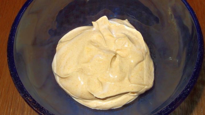 Eine cremige Quarkspeise liegt in einer blauen Sch&uuml;ssel auf einem Holztisch und l&auml;dt zum Genie&szlig;en ein.