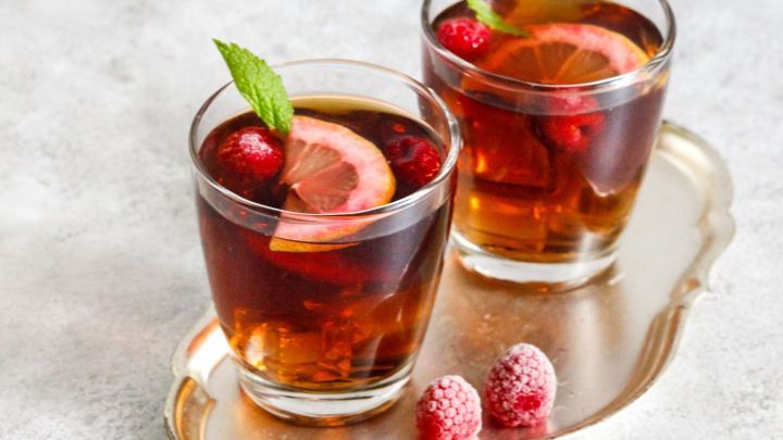 Zwei Gl&auml;ser Cola mit Himbeer Wodka stehen auf einem Tablett, garniert mit Himbeeren und Zitronenscheiben in einem hellen Umfeld.