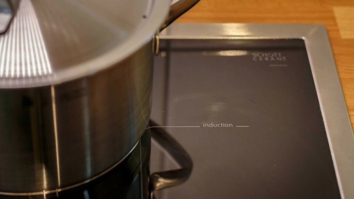 Ein Topf steht auf einem Herd, w&auml;hrend er Wasser erhitzt; der Herd hat ein modernes, glattes Design.