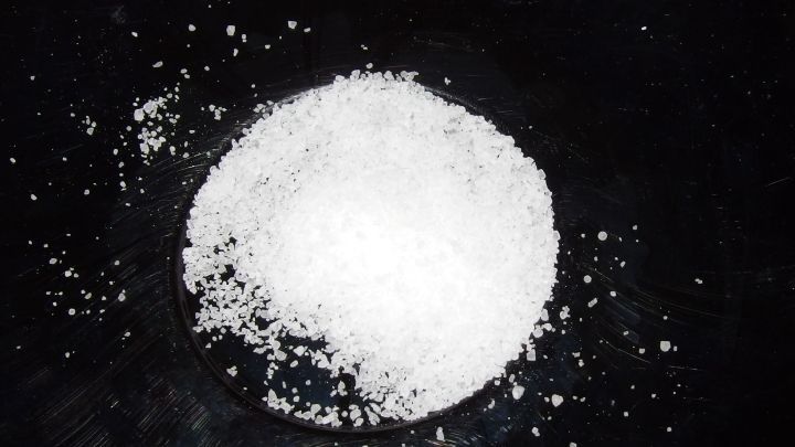 Ein Haufen Kochsalz liegt auf einer dunklen Oberfl&auml;che und kann zur Entfernung von Warzen genutzt werden.