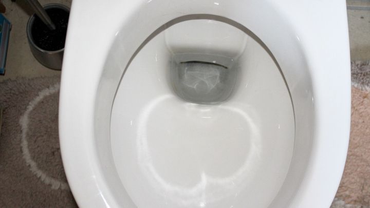 Ein Toilettenbecken zeigt metallische Kratzer im Keramik, umgeben von einem sauberen Badezimmer.