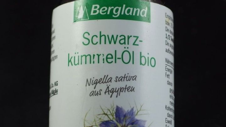 Eine Flasche mit fl&uuml;ssigem Schwarzk&uuml;mmel&ouml;l steht vor schwarzem Hintergrund und zeigt den Namen und die Inhaltsstoffe.