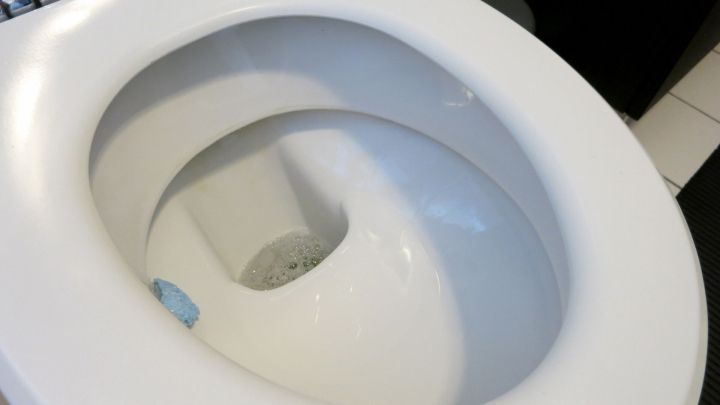 Eine wei&szlig;e Toilette steht im Badezimmer, das Wasser im Abfluss zeigt Anzeichen von Verschmutzung und Ablagerungen.