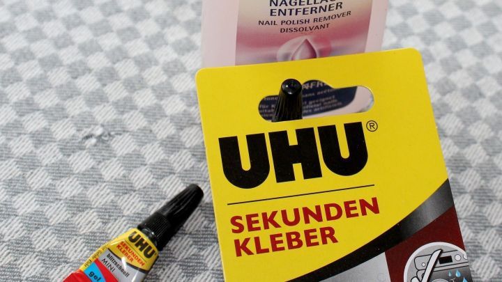 UHU Sekundenkleber-Tube und Nagellackentferner markiert mit "UVERISH" auf kariertem Untergrund; Kleber f&uuml;r schnelle Reparaturen.