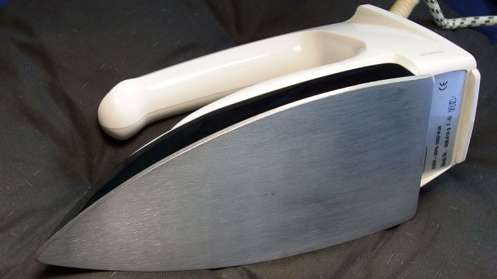 Ein B&uuml;geleisen liegt auf einem weichen Untergrund, bereit zum Reinigen mit Glaskeramikfeldreiniger, um Schmutz zu entfernen.