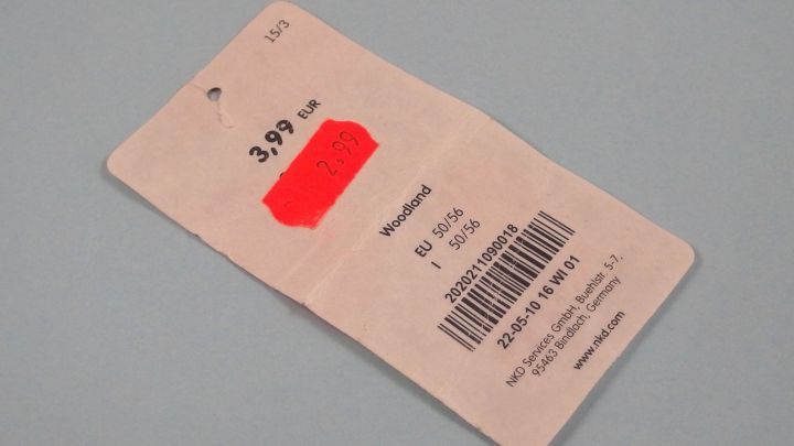 Eine Preisschilder ist auf einem Tisch platziert, markiert mit einem roten Aufkleber, um Informationen &uuml;ber ein Produkt zu zeigen.