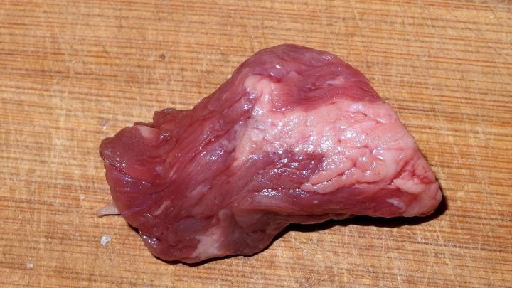 Ein St&uuml;ck Rindfleisch liegt auf einem Holzbrett, bereit zur Zubereitung f&uuml;r die Warzenbehandlung in der K&uuml;che.