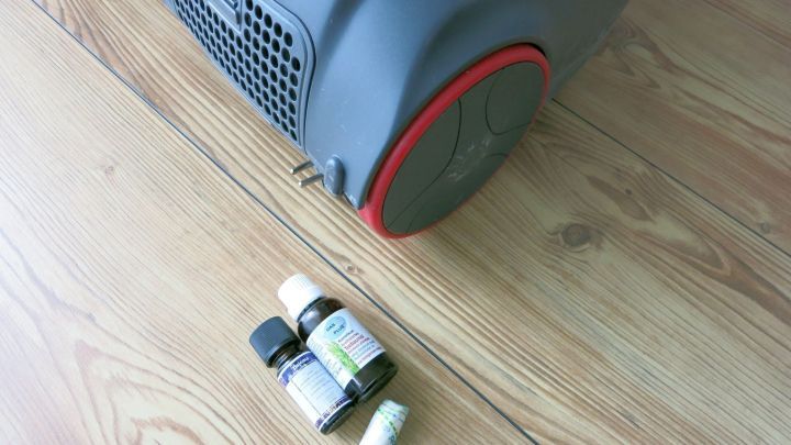 Ein Staubsauger steht auf einem Holzboden, daneben liegen &auml;therische &Ouml;le f&uuml;r die Herstellung von Duftst&auml;bchen.
