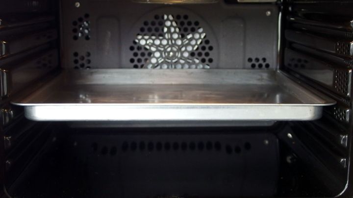 Ein Backofen mit einer leeren Backblech im Inneren wird betrachtet, bereit f&uuml;r die Reinigung mit Essig-Sp&uuml;li.