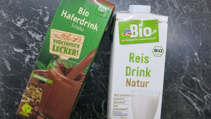 Zwei Getr&auml;nkekartons stehen nebeneinander auf einer dunklen Oberfl&auml;che. Links ist ein Bio-Haferdrink, rechts ein Bio-Reisdurch, beide ohne Kuhmilchprodukte.
