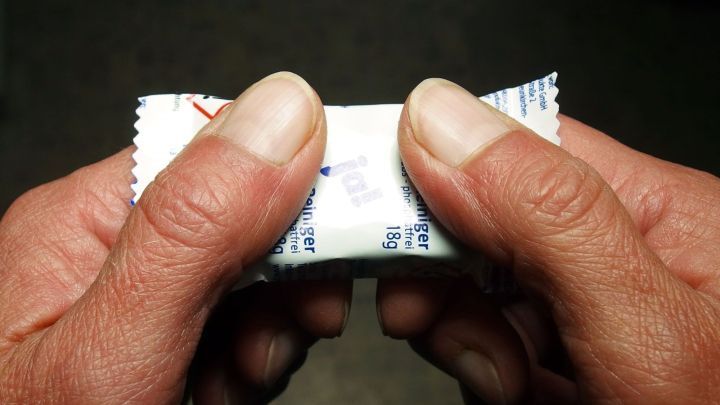 Zwei H&auml;nde dr&uuml;cken einen Geschirrsp&uuml;ltab, um ihn f&uuml;r die Verwendung in der Sp&uuml;lmaschine vorzubereiten.