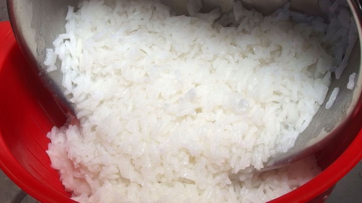 Gekochter Reis liegt in einem roten Sieb, w&auml;hrend Reiswasser abtropft, bereit zur Verwendung gegen Durchfall.