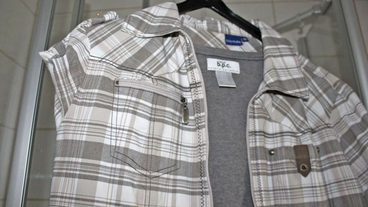 Ein kariertes Hemd h&auml;ngt auf einem Kleiderb&uuml;gel in einem hellen Raum, bereit zum B&uuml;geln f&uuml;r einen gepflegten Look.