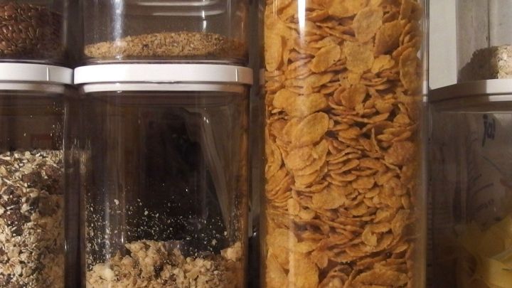 Gl&auml;ser mit Lebensmitteln, darunter Flocken, stehen ordentlich in einem Regal; ideal f&uuml;r die Aufbewahrung ohne Lebensmittelmotten.