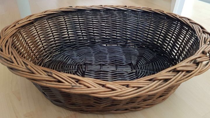 Ein Weidenkorb steht auf einem hellen Boden und zeigt eine feingeflochtene Struktur, bereit zur Verwendung oder Restaurierung.