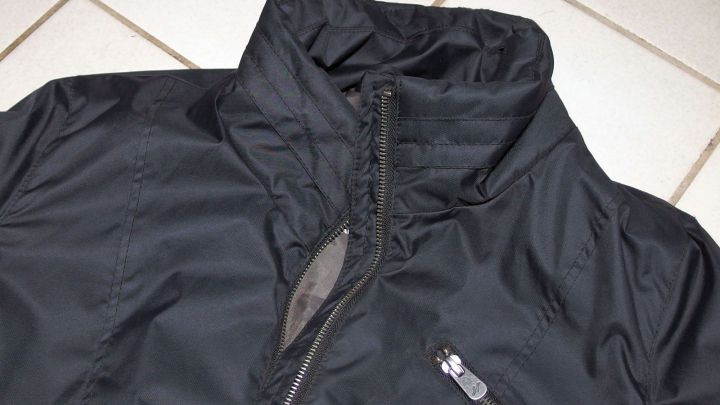 Ein schwarzer Anorak liegt auf einem hellen Bodenfliesen, bereit, im Sodabad gewaschen zu werden, um Harzflecken zu entfernen.