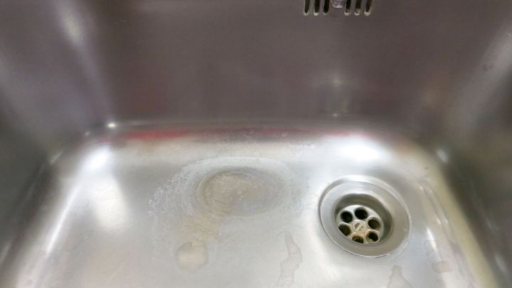 Eine Edelstahlsp&uuml;le mit hartn&auml;ckigen Flecken steht im Mittelpunkt, sie wirkt unrein und ben&ouml;tigt Reinigung.