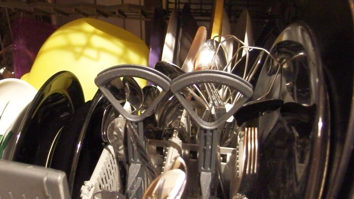 Ein Geschirrsp&uuml;ler zeigt sauberes Geschirr und Besteck, das auf das Abpumpen von Wasser wartet, in einer K&uuml;chenumgebung.