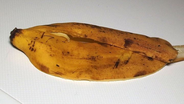 Eine braune Bananenschale liegt auf einer wei&szlig;en Oberfl&auml;che, bereit f&uuml;r die Anwendung zur Entfernung von Dornwarzen.