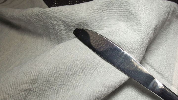 Ein Messer liegt auf einem blassen Tuch, das zur Entfernung von Blutflecken genutzt wird, vermutlich in einem gem&uuml;tlichen Raum.