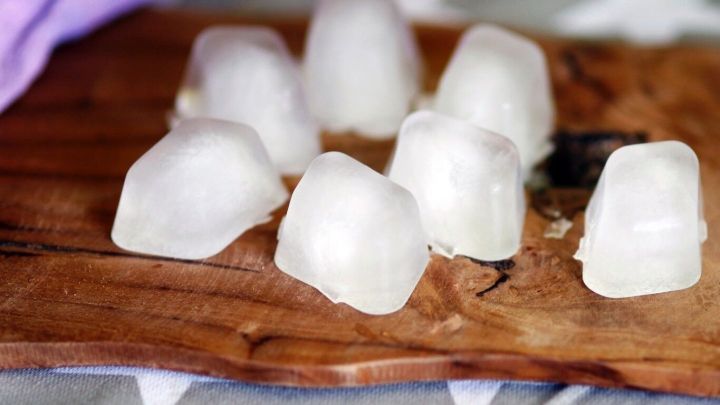 Eisw&uuml;rfel liegen auf einem Holzbrett, bereit f&uuml;r &bdquo;Notf&auml;lle&ldquo;, um Getr&auml;nke zu k&uuml;hlen oder Schmerzen zu lindern.