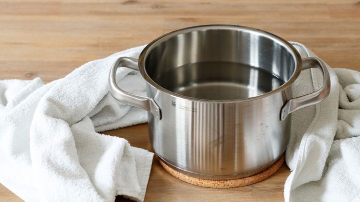 Ein Topf mit Wasser steht auf einem Untersetzer, umgeben von einem Handtuch, bereit zum Inhalieren gegen Ohrenschmerzen.