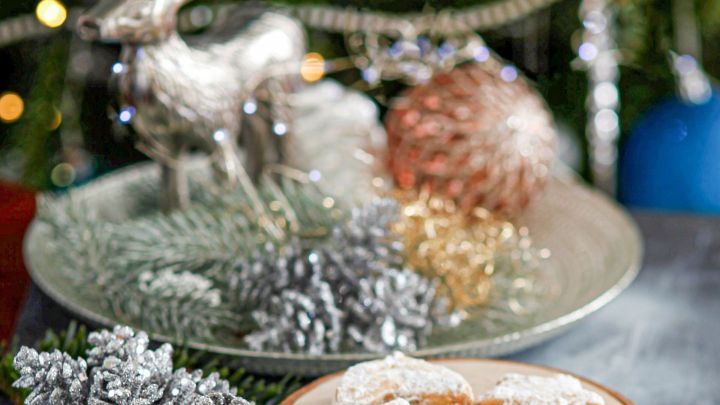 S&uuml;&szlig;es Geb&auml;ck liegt auf einem rustikalen Holzbrett, umgeben von festlicher Dekoration und einem dekorativen Rentier.