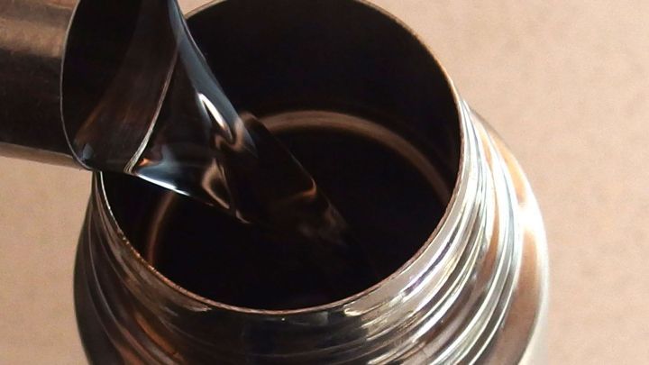 Eine Edelstahlkanne wird ge&ouml;ffnet, w&auml;hrend dunkle Fl&uuml;ssigkeit hineingegossen wird, um in der K&uuml;che Strom zu sparen.