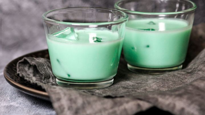 Zwei Gl&auml;ser mit gr&uuml;nem Getr&auml;nk stehen auf einem dunklen Teller. Ein graues Tuch liegt im Hintergrund.