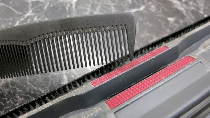 Eine Staubsaugerb&uuml;rste wird mit einem Kamm gereinigt, um Verunreinigungen effizient zu entfernen.