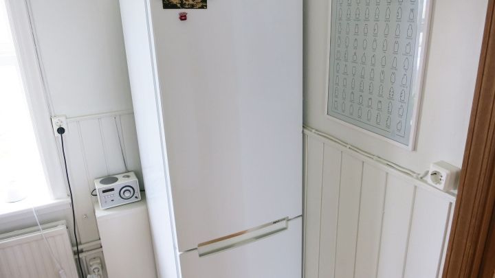 Ein K&uuml;hlschrank steht in einer modernen K&uuml;che, auf seiner T&uuml;r sind Notizen und eine &Uuml;bersicht angebracht f&uuml;r die Nutzung als Whiteboard.