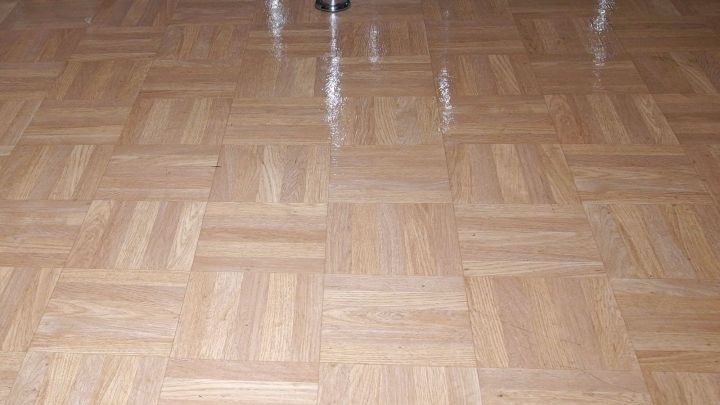 Sauberer Laminatboden gl&auml;nzt streifenfrei, reflektiert Licht in einem Wohnraum mit einer einfachen, hellen Holzoptik.