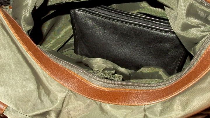 Eine Handtasche mit einer ordentlichen Anordnung, in der eine schwarze Geldb&ouml;rse sichtbar ist, liegt in einem hellen Innenraum.