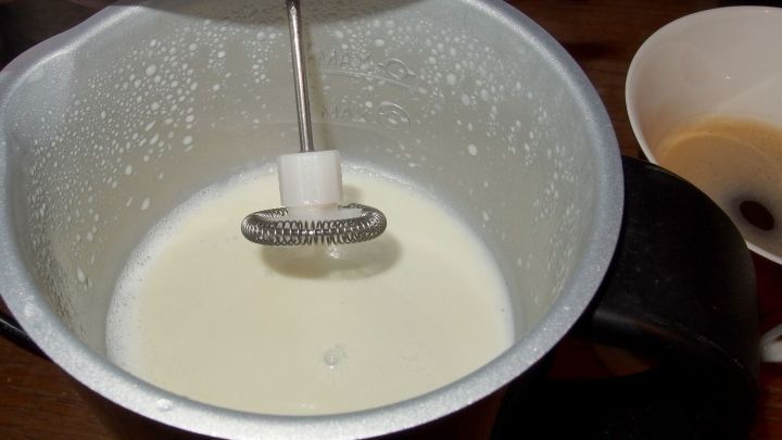 Ein Milchaufsch&auml;umer kreiert gesch&auml;umte Milch in einem Beh&auml;lter, w&auml;hrend sich ein Kaffeefilter daneben befindet.