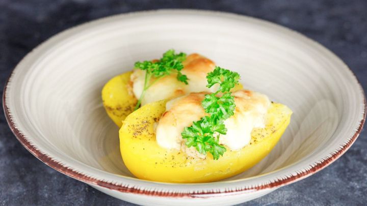 Gef&uuml;llte Ofenkartoffeln liegen ansprechend in einer hellen Schale, dekoriert mit frischer Petersilie.